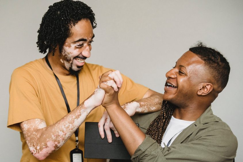 laughing black male colleagues clasping hands in excitement together