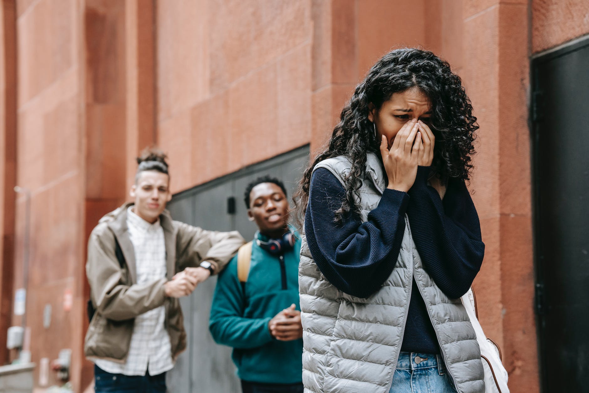 multiethnic male students gossiping about sad crying woman