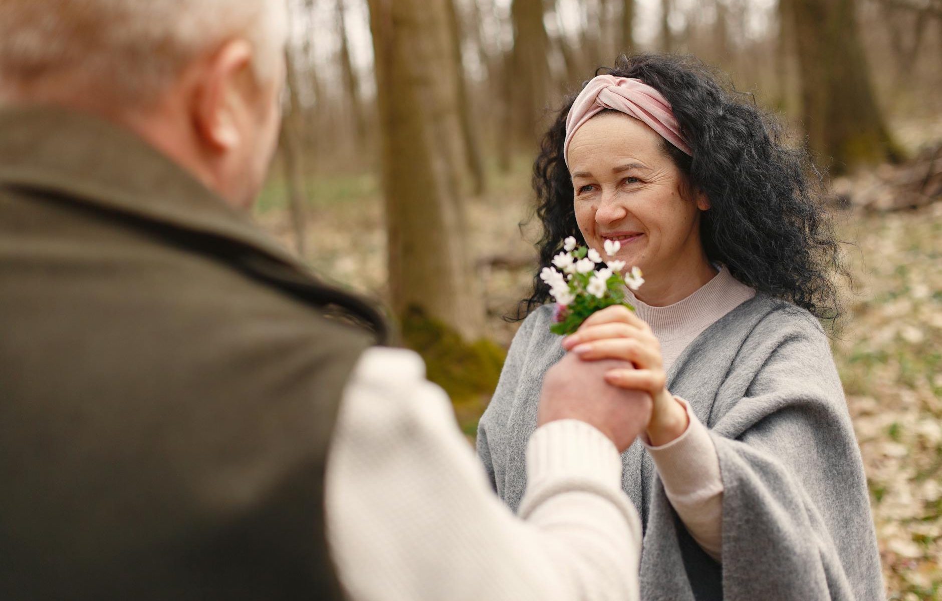 happy senior couple in love with flowers in forest