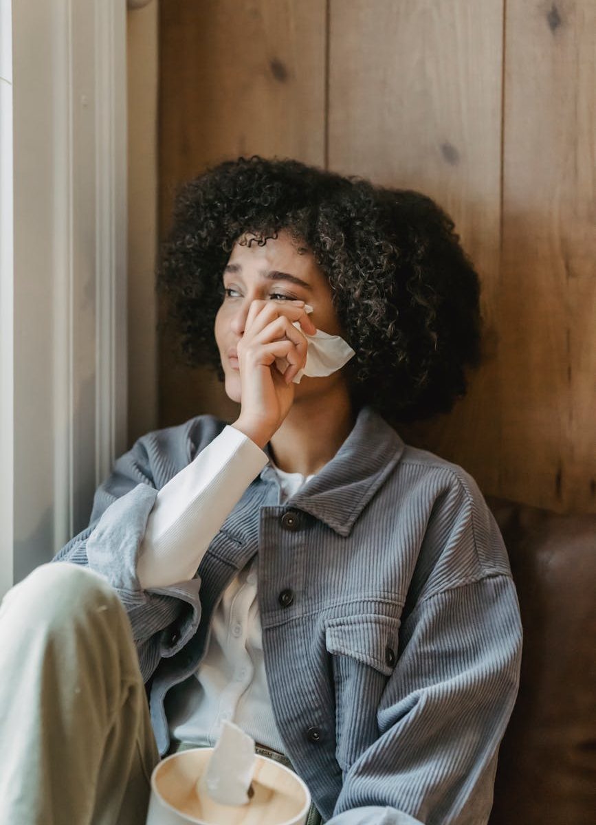 sad young ethnic lady crying near window at home